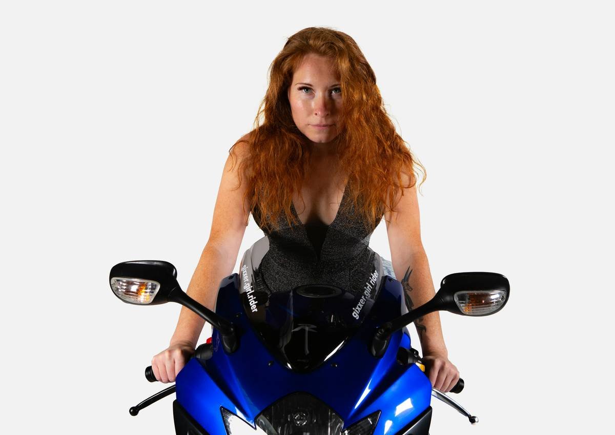 A woman sitting on a blue motorcycle posing for a picture