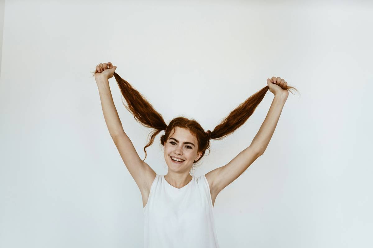 Funny school girl on the white background holds her tails and smiling. Shool concept
