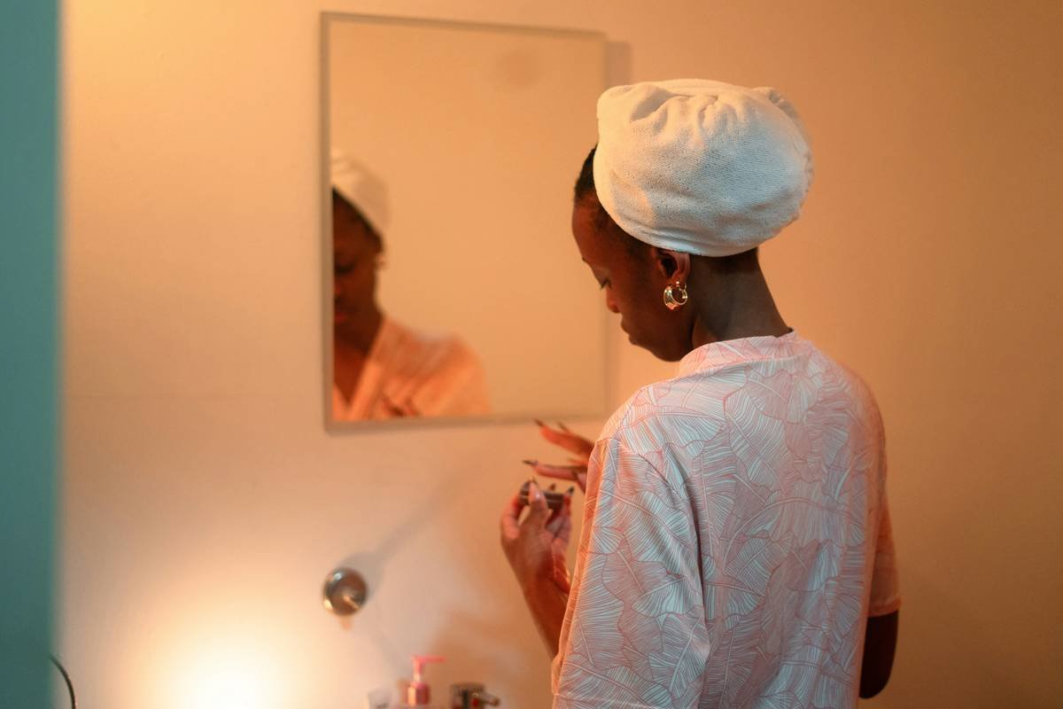 Woman applying makeup in front of a mirror.