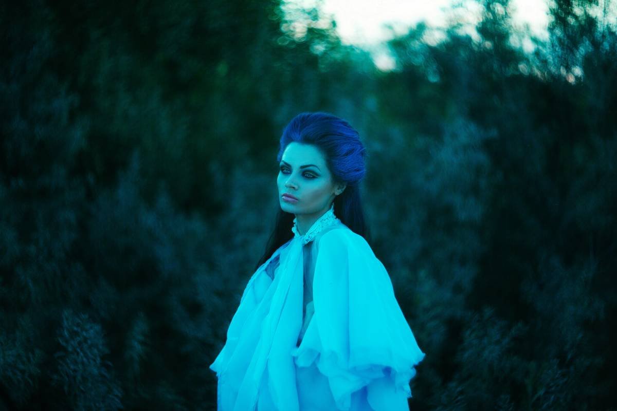 Woman with blue hair in ethereal white dress outdoors