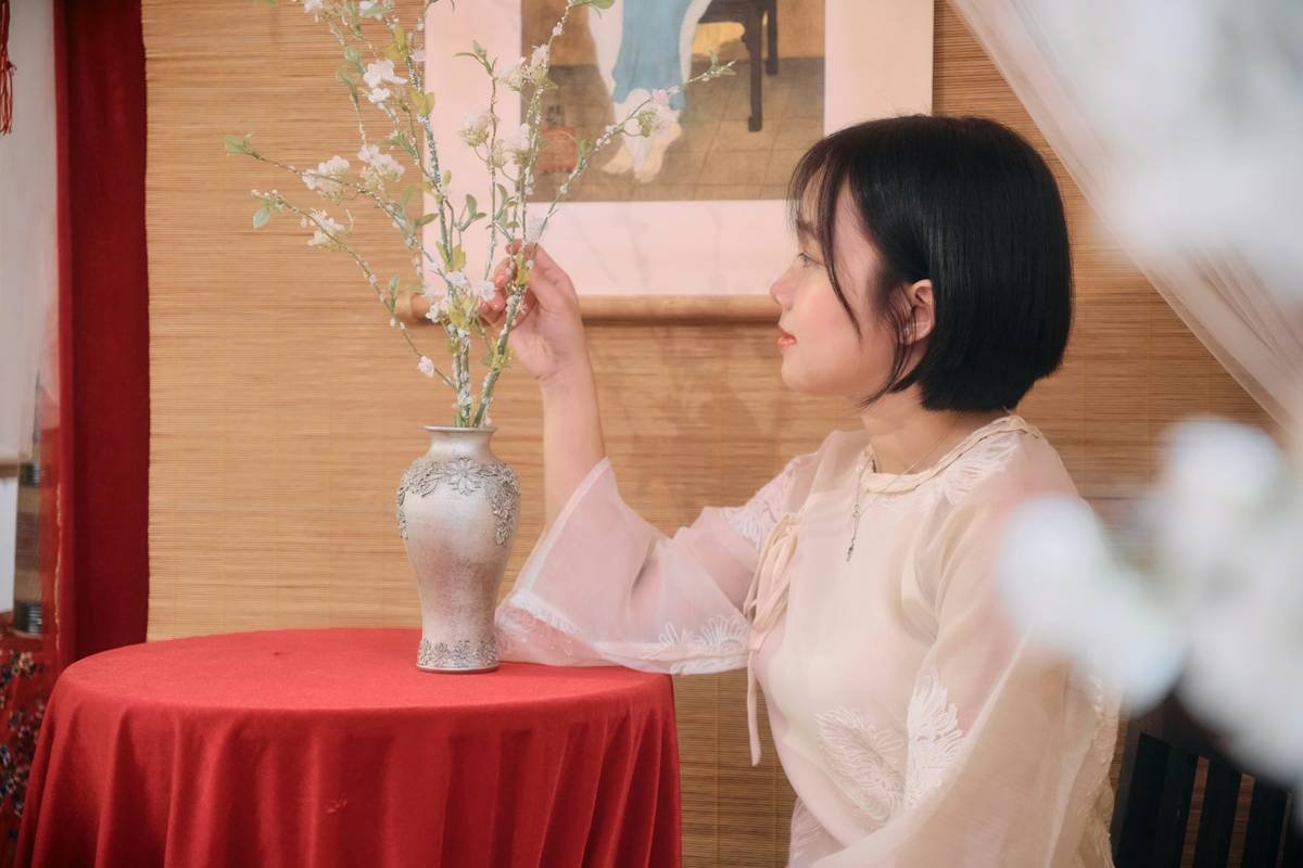 Young woman arranging flowers in a vase on a table