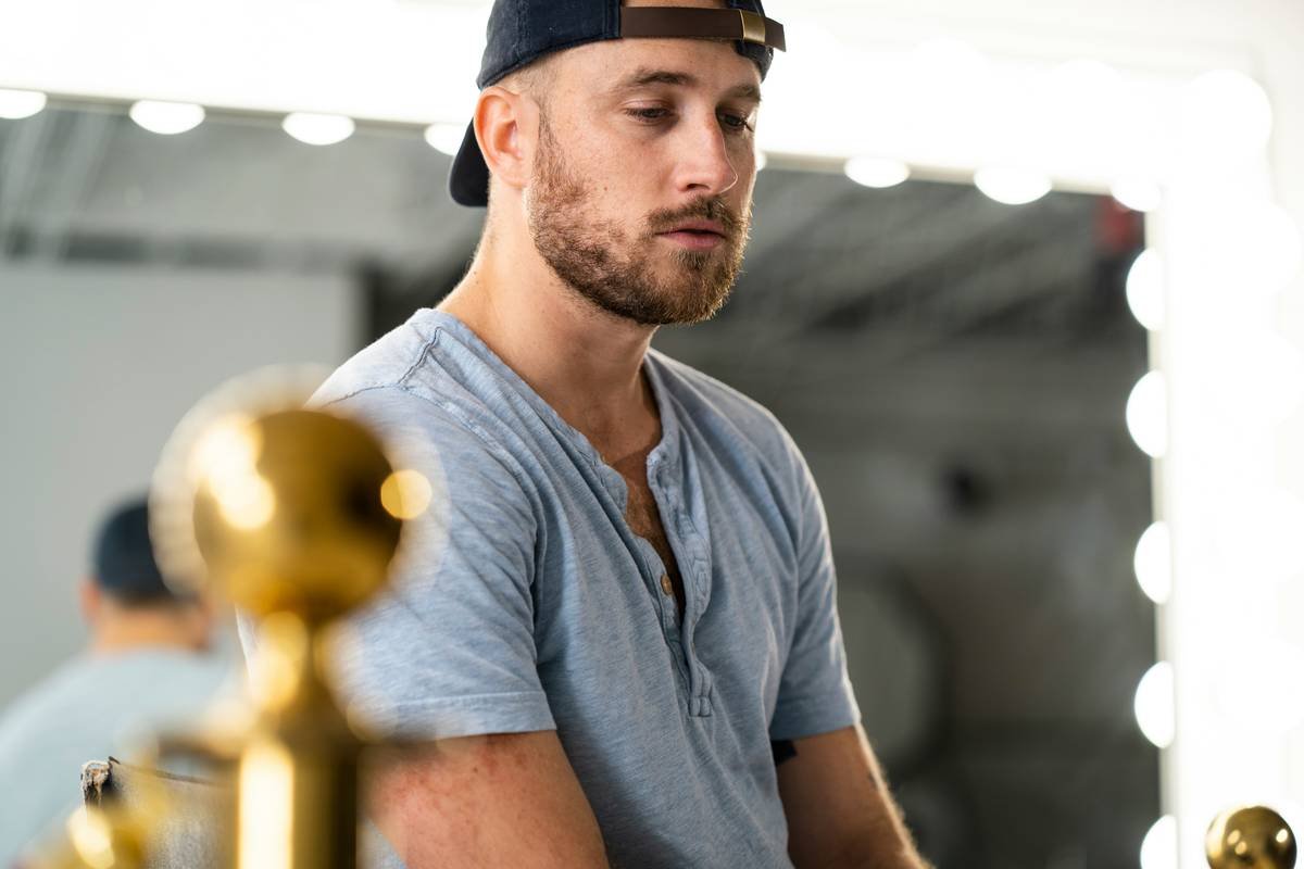 Contemplative man with blue shirt and hat inside a studio