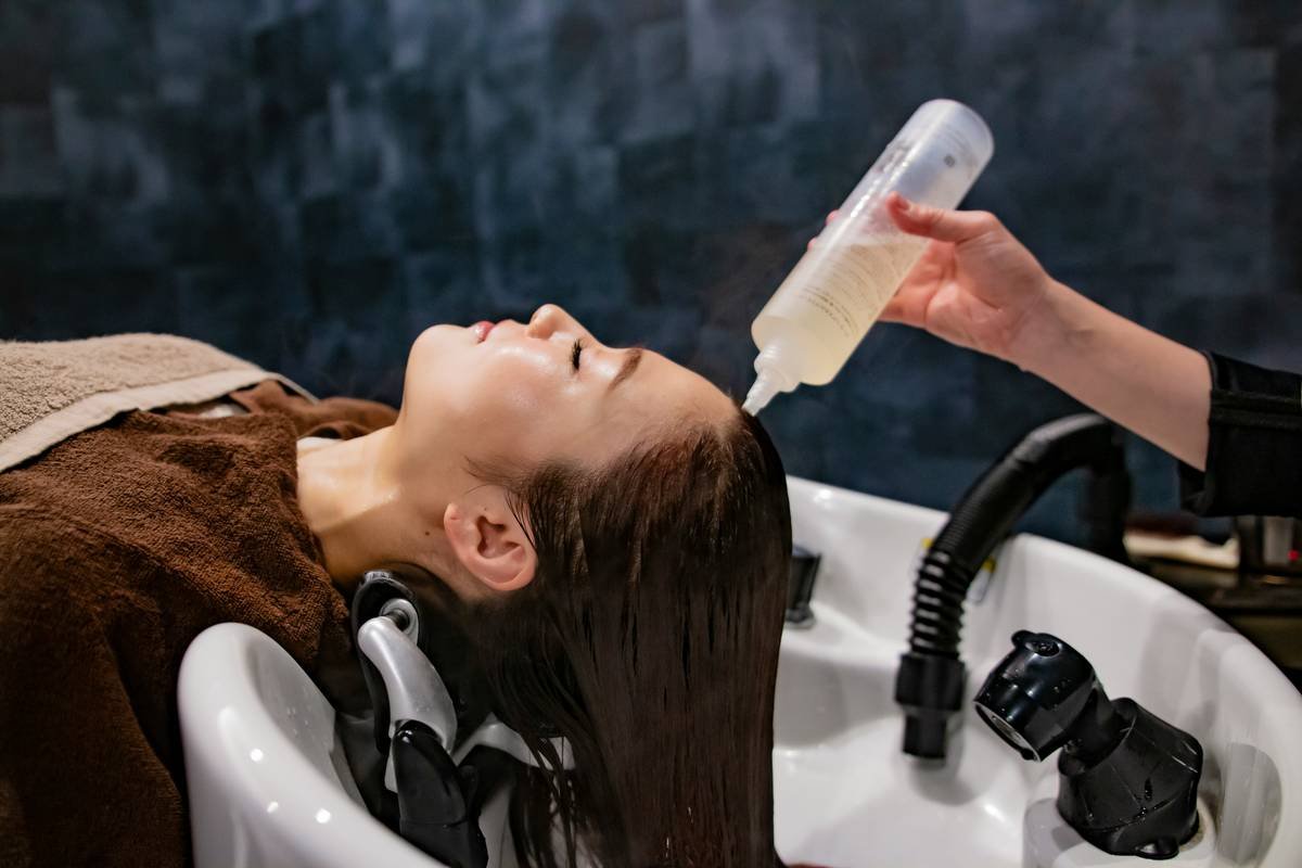 Woman applying hair moisture mask to damp hair in bathroom