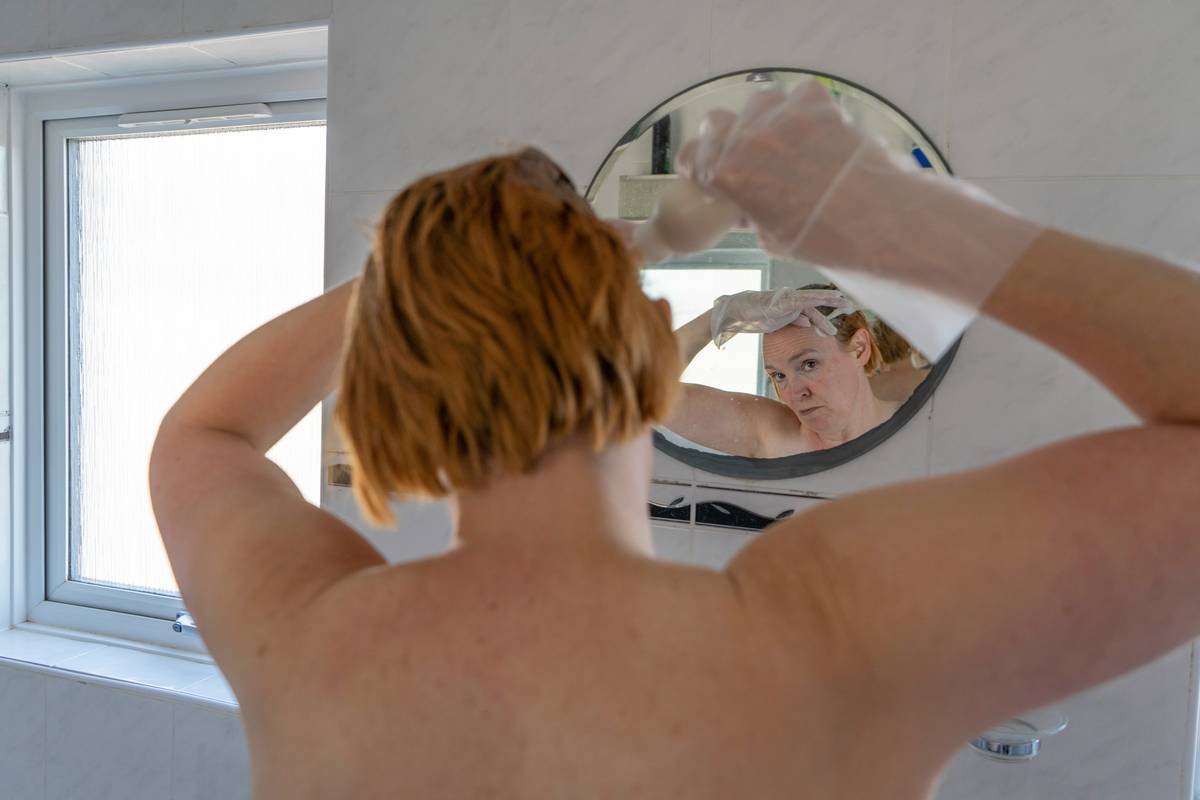 Woman applying intensive hair nourisher to damp hair in bathroom